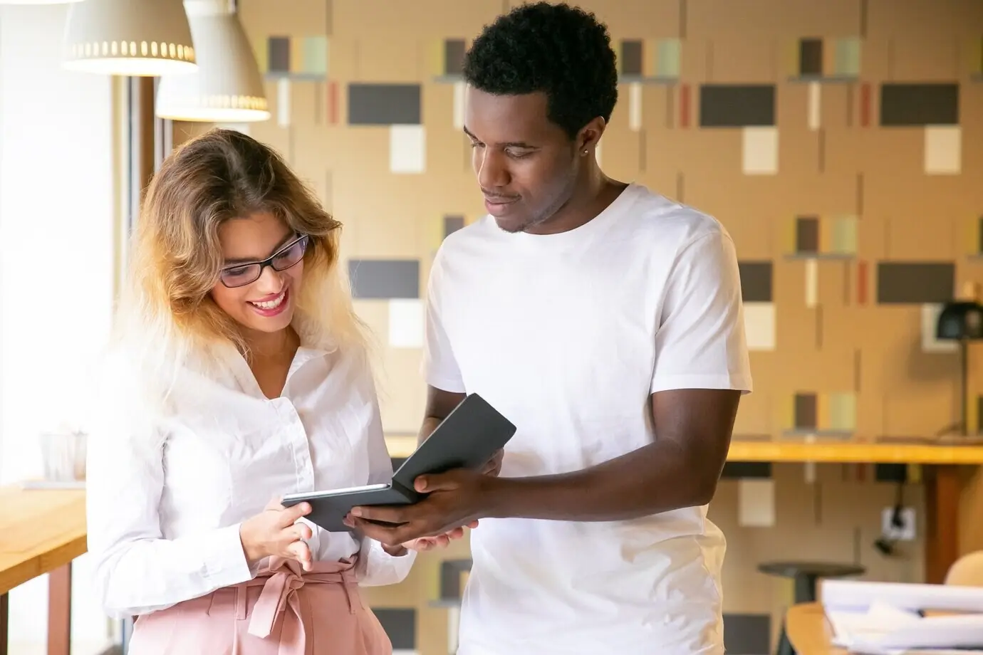 Ein afroamerikanischer Mann präsentiert einer blonden Frau ein neues Design.