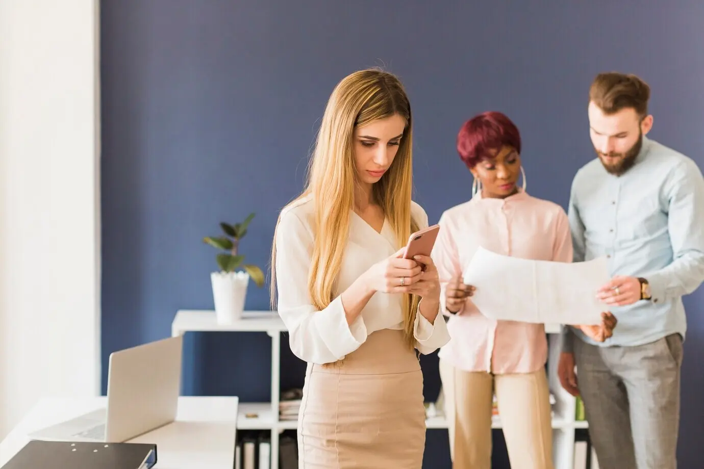 Frau nutzt ein Smartphone in der Nähe von Kollegen